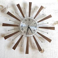 Front view of the sunburst wall clock showing the full clock face and wooden rays extending outwards.
