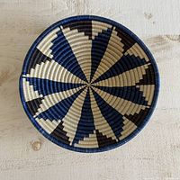 Top-down view of the round woven basket showing blue, black, and tan geometric star design pattern.