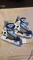 Pair of CCM ice hockey skates shown from side view on floor, both skates.