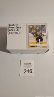 Box labeled '2022-23 Upper Deck Series 2 (251-450)' with a hockey card showing a player in a black and yellow jersey on top of the box.