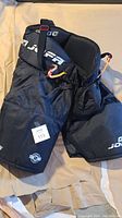 Full view of black padded hockey pants with Jofa and FX branding.