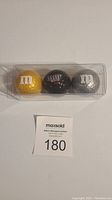 Set of three M&M's collectible golf balls in yellow, brown, gray colors in clear plastic case.