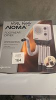 Box front showing image and branding of Noma Footwear Dryer with flexible hoses and control panel.