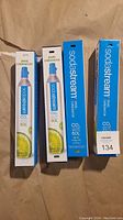 Photo showing four Sodastream spare carbonator CO2 cylinders in original boxes, two white and two blue boxes, each labeled for 60L use.