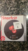 Front view of the Starfrit kitchen scale box showing product image, brand, and capacity information.