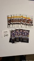 Twelve unopened Topps NHL hockey sticker packs with white and yellow packaging arranged in a row with five unopened black/purple 2021-22 NHL sticker packs below them.