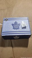 Closed light blue Toronto Maple Leafs branded gift box with sticker and logo visible.