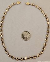 Full view of the necklace laid out with a quarter for scale showing the link pattern and length.