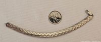 Full view of the 6 1/4 inch silver bracelet next to a quarter for scale.