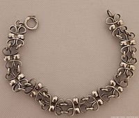 Full view of bracelet laid flat showing alternating bow-shaped and bar links