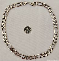 Full view of chain coiled around a Canadian quarter for scale showing link pattern and overall length