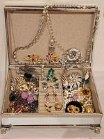 Open mirrored jewelry box displaying assorted jewelry inside