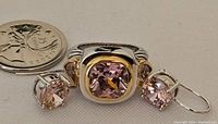Ring and two earrings with vibrant pink stones and sterling silver setting, placed beside a quarter for scale.
