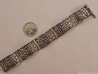 Full view of the 7 inch sterling silver vintage Egyptian panel bracelet along with a coin for scale.