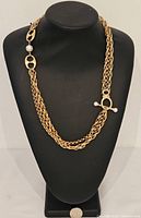 Gold tone necklace displayed on necklace bust, showing double linked chain design, two toggle clasps with pearl accents and black enamel details.