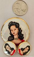 Photo showing brooch and two earrings alongside a quarter for size reference, highlighting the painted portrait's details and gold-tone edging.