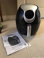 Full view of Power Air Fryer XL with manual on carpeted floor.