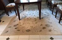 Full view of the patterned area rug under a wooden table with surrounding chairs on tile floor