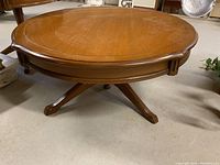Front view of the round mahogany coffee table showing the scalloped edges and wood grain top.