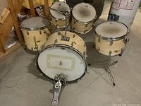 Full view of kit: bass drum, three toms, pedal on concrete floor