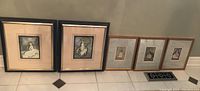 Full view of all five framed prints, two larger and three smaller, arranged on the floor.