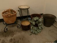 Wide photo shows all items including mosaic top table, wicker planters, flared plastic planter, ceramic planter, grapevine wreath, and metal stand.