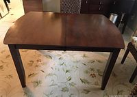 View of the mahogany dining table top showing the rectangular shape with rounded corners and tapered legs.