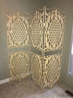 Front view of the three-panel metal screen showing detailed cast iron lattice and ornamental scrollwork design.