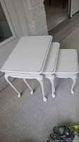 Three white painted wood nesting tables stacked inside each other, showing size range and white antiqued finish.