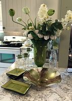 Full view of lot showing tall green vase with artificial flowers, ceramic plates, decorative bowl and candle holders