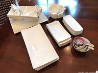 Overview of all dishes including rectangular sushi plates, small patterned bowls, white spoons and spoon rests arranged on a table.