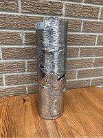 Front view of the aluminum cast vase showing detailed birch bark texture and uneven top edge