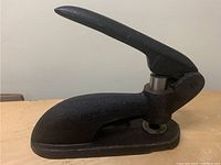 Full side view of the cast iron lever punch showing overall shape and lever handle.