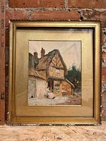 Framed watercolour painting showing full scene with house, seated figure, and surroundings under glass.