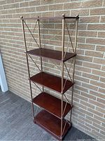 Front angled view of the full etagere showing four wooden shelves and metal frame with cross braces and finials.