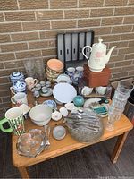 Full view of assorted kitchen and tableware on wooden table against brick wall