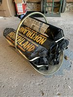 Fire logs stacked in metal holder on concrete floor, showing Northland branding on packaging.