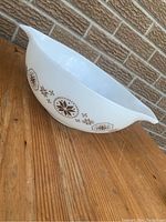 Side view of white Pyrex mixing bowl showing the Amish Star brown pattern and pouring spout