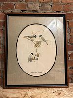 Framed art print showing three chickadee birds on a branch with an oval linen mat and rectangular wooden frame.