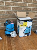 Photo showing the Simer 2300 water pump alongside its original box and a user manual label.