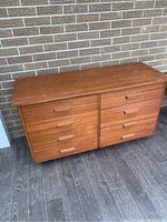 Full dresser showing six drawers and overall shape against a brick wall background.