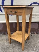 Front angled view of vintage hardwood side table showing drawer and lower shelf, natural wood finish and sturdy tapered legs.