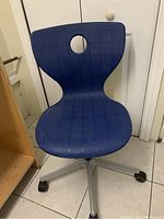Front view of blue ergonomic office chair with circular hole in backrest and square patterned textured seat and back