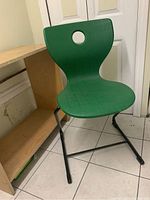 Front view of green molded plastic seat and black tubular base