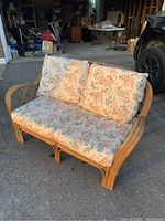Front view of two-seater rattan loveseat with floral cushions