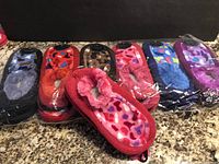 12 pairs of mixed color slipper socks Snuggs in packaging, neatly stacked in rows on a counter.