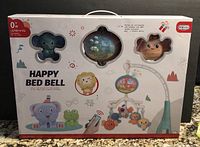 Front of the brand new box showing the Happy Bed Bell brand, animal figures, and the mobile assembled as an example.