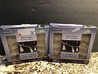 Two unopened boxes of Catalina Silver Mesh String Lights placed side by side on a granite surface.