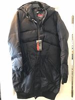 Front view of new black Nikita women's down jacket with tags hanging, showing zip front and hood.