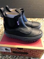 Photo showing Vans boots on top of original Vans box, black leather upper with detailed stitching and black elastic panels